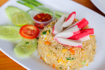 Delicious Seafood Fried Rice: A vibrant plate of freshly made fried rice, garnished with colorful crab sticks, cucumber, tomato slices, and a spicy dipping sauce.
