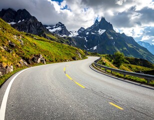 A winding mountain road snakes through lush greenery, leading to snow-capped peaks under a partly cloudy sky.