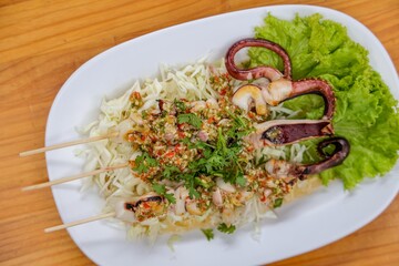 Grilled Octopus Delight: Culinary masterpiece, with the appetizing presentation of skewered octopus, accompanied by vibrant cabbage salad and fresh lettuce.