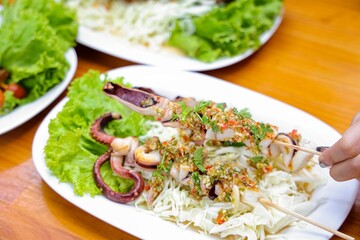 Grilled Squid with Flavor: A mouthwatering image showcasing grilled squid skewers, artfully presented on a bed of fresh lettuce and vibrant greens, promising a burst of flavor and culinary delight.