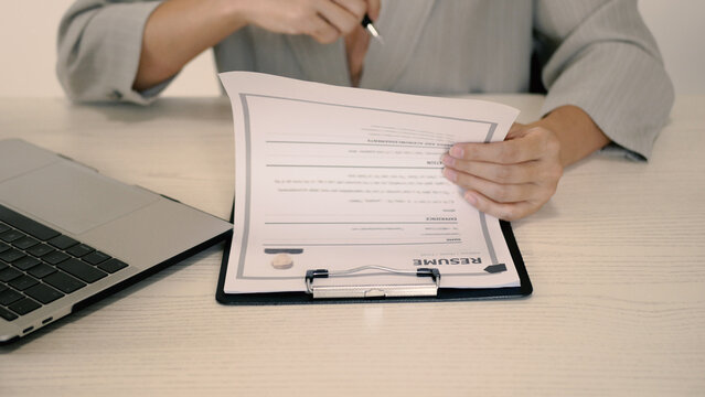 Young businesswoman holding resume and evaluating. Reviewing profile of job applicants to find new candidates to work together. Recruitment concept