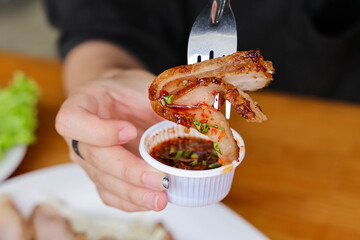 Grilled Pork with Dipping Sauce: A close-up shot features a piece of succulent grilled pork being dipped into a flavorful sauce, highlighting culinary artistry and the joy of savoring delicious food.