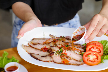 Flavorful Dish: A person carefully drizzles a savory sauce over a plate of expertly prepared meat,...