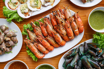 Sumptuous Seafood Feast: A vibrant overhead shot of a tantalizing array of seafood dishes, artfully arranged on a wooden surface. The scene is a testament to culinary artistry.
