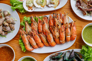 Seafood Feast: A lavish spread of cooked seafood dishes, artfully arranged on a wooden table, including plump prawns, mussels, scallops, and other delicacies.