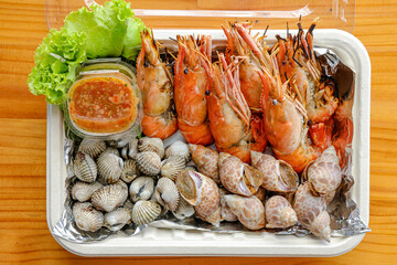 Seafood Platter Delight: A mouthwatering seafood platter, artfully arranged with succulent grilled prawns, clams, shells, and vibrant side, presented on a wooden surface, ready to be savored.
