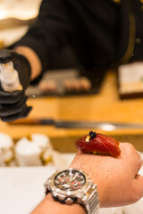 Japanese Omakase meal. Aging raw akami tuna sushi served on a back of hand.