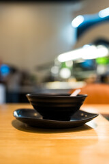 Empty of black bowl and black saucer for eating Sukiyaki on wood table
