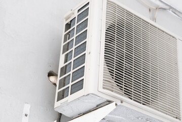Close-up image of an outdoor air conditioning unit attached to a building wall