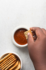 overhead view of tomato sauce in a white ramekin, top view of tomato sauce and crackers on white countertop