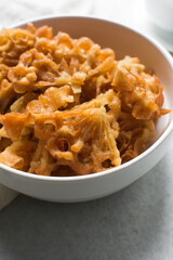 Overhead view of sassafa northern nigerian snack in a white bowl, top view of rosette cookies on a white background