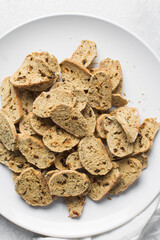 overhead view of slices of savory biscotti with dip, top view of thinly sliced bread chips with sauce, top view of crostini bread slices on marble countertop