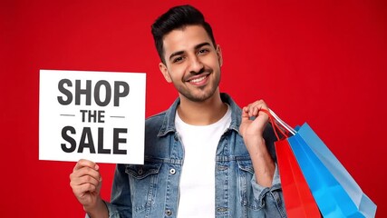 Excited young man holding shopping bags and 'Shop the Sale' sign, promoting a fantastic discount event