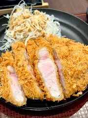 Crispy tonkatsu, a Japanese-style breaded and deep-fried pork cutlet, served with shredded cabbage and drizzled with savory sauce. A delightful balance of crunchy texture and juicy meat.