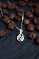 Elegant Coffee Bean Pendant Necklace on Dark Slate with Roasted Coffee Beans, Stylish Jewelry.
