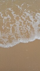 Foamy white ocean waves on the sandy beach