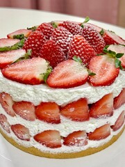 Strawberry cake with soft fluffy layers, topped with fresh strawberries and smooth cream, showcasing vibrant red fruit, delicate textures, and sweet inviting appearance in close-up detail