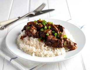 Savory, browned meat pieces atop a bed of fluffy white rice, garnished with fresh green onions, served on a pristine white plate.