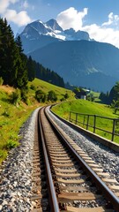Fototapeta premium Winding railway track through alpine valley, mountains in the background