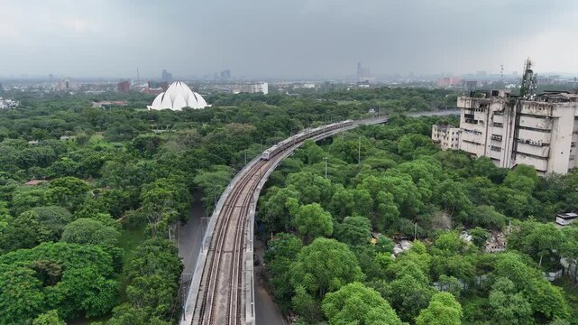 Aerial shot of Metro train running beside the lotus Temple in New Delhi, India