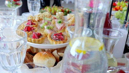 Gourmet appetizers featuring cucumber, ham, cheese canapes and mini pies displayed alongside cold lemonade at professional catering event