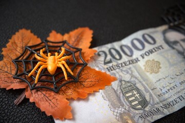 Hungarian 20000 forint note decorated with autumn leaves, spiderweb, and spider. Halloween money concept.