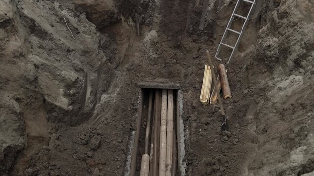 Excavation progression: digging deeper into earth with ladder and timbers.