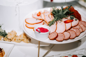 Sliced meats on a decorative platter at a festive gathering in the evening