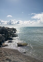 A breakwater made of large boulders on a Black Sea beach with small pebbles on a sunny day in mid-September