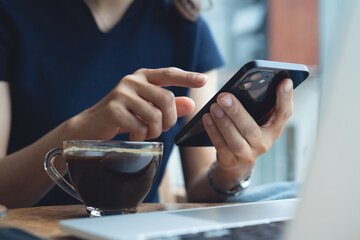 Woman using mobile phone with laptop computer on table in coffee shop. Female freelancer working at cafe, using smartphone, online shopping and internet banking