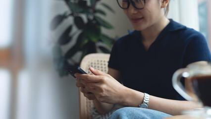 Asian woman using smartphone, browsing the internet, social networking on mobile app at cafe. Woman...
