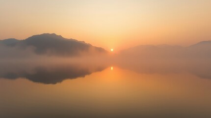 Naklejka premium Sunrise over serene lake: A serene vista unveils, as the sun gently ascends, casting a golden hue over the calm waters and distant misty mountains. Witness the enchanting interplay of light.