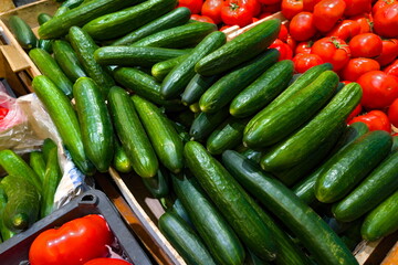 Fresh cucumbers and ripe tomatoes displayed at a vibrant market stall during a sunny afternoon in summer