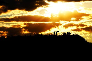 Silhouettes of people on hilltop with sunset over