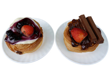 Two pastries look delightful with their fresh strawberry toppings, one glazed with blueberry and other with chocolate
