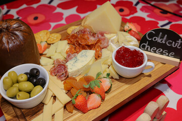 Artisan Cheese Board: A culinary masterpiece features an array of fine cheeses, complementing cold cuts, olives, and strawberries arranged artfully for a delightful tasting experience. 