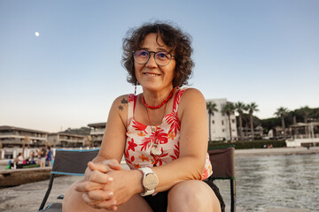 Portrait of a happy senior woman at the beach at sunset