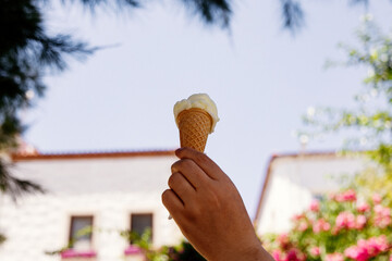 Ice cream cone in the hand of a woman on a background of flowers