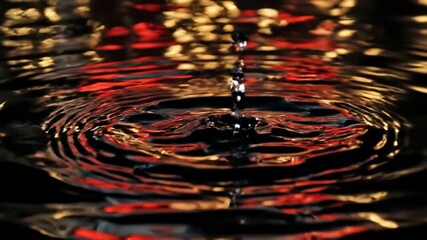 Dramatic macro shot of a droplet creating ripples on a dark liquid surface, reflecting vibrant red and gold city lights. - Powered by Adobe