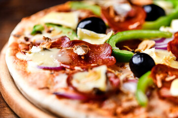 Pizza with chorizo ​​sausage, mozzarella cheese, green pepper and black olives. Rustic wooden background. Soft focus.	