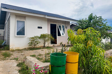 This image shows a subsidized permanent house painted white with a simple design, located in a residential complex.