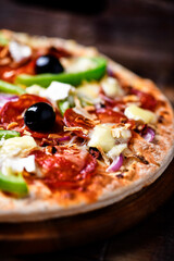 Pizza with chorizo ​​sausage, mozzarella cheese, green pepper and black olives. Rustic wooden background. Soft focus.	