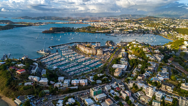 An aerial drone view focusing on the bustling marina in Noum&eacute;a, New Caledonia. Hundreds of yachts and sailboats are docked in the harbor against the city backdrop