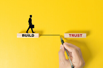 Build trust symbol. Concept words Build trust on wooden blocks on a beautiful yellow table yellow background. Businessman hand. Business and build trust concept, copy space