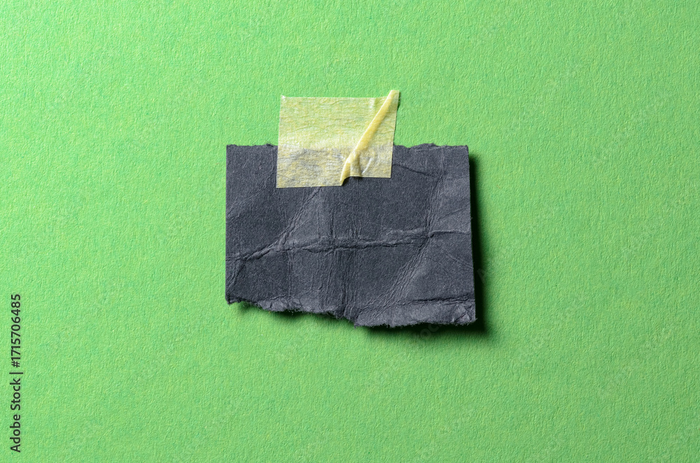 Poster isolated cut out torn piece of black paper note with rough texture edges and adhesive tape with copy