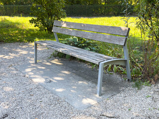Empty wooden park bench on sunny day in tranquil garden setting