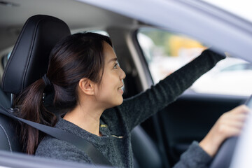 Woman driving car adjusting rear view mirror inside