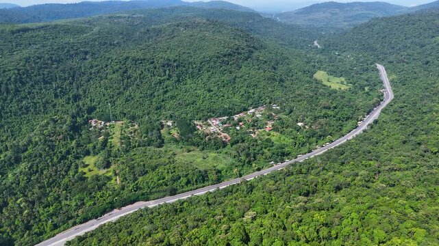 Drone footage of the aerial view of a winding road cutting through lush green forest. Scenic highway number 304 in Thailand links the Bangkok area to Nakhon Ratchasima in the northeastern region
