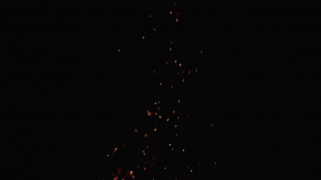 Slow motion of sparks and embers from campfire flying over black background