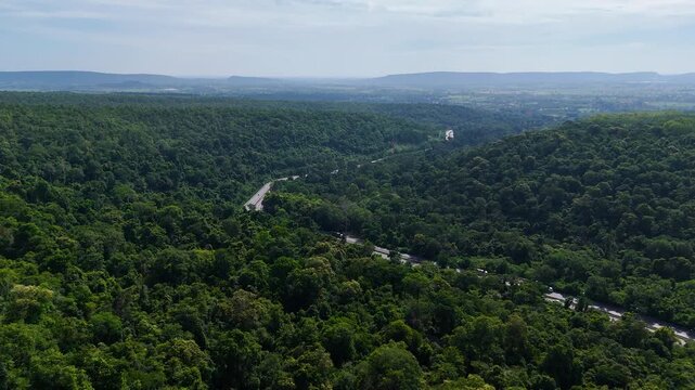 Drone footage of the aerial view of a winding road cutting through lush green forest. Scenic highway number 304 in Thailand links the Bangkok area to Nakhon Ratchasima in the northeastern region